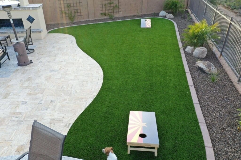 Outdoor living space with turf, fire pit, and retaining wall